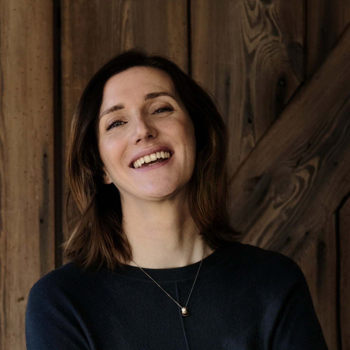 Lena von der Vandebag Manufaktur steht lachend vor einer alten Bretterwand