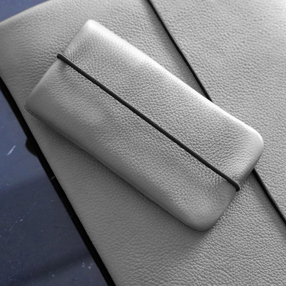 Leder Handyhüllle in grau liegt auf einer passenden grauen Macbookhülle aus Leder