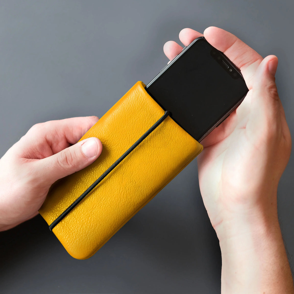 Handy wird in gelbe Lederhülle gesteckt