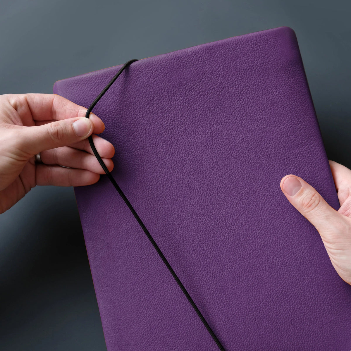 Macbookhülle aus lila Leder wird mit Gummiband verschlossen