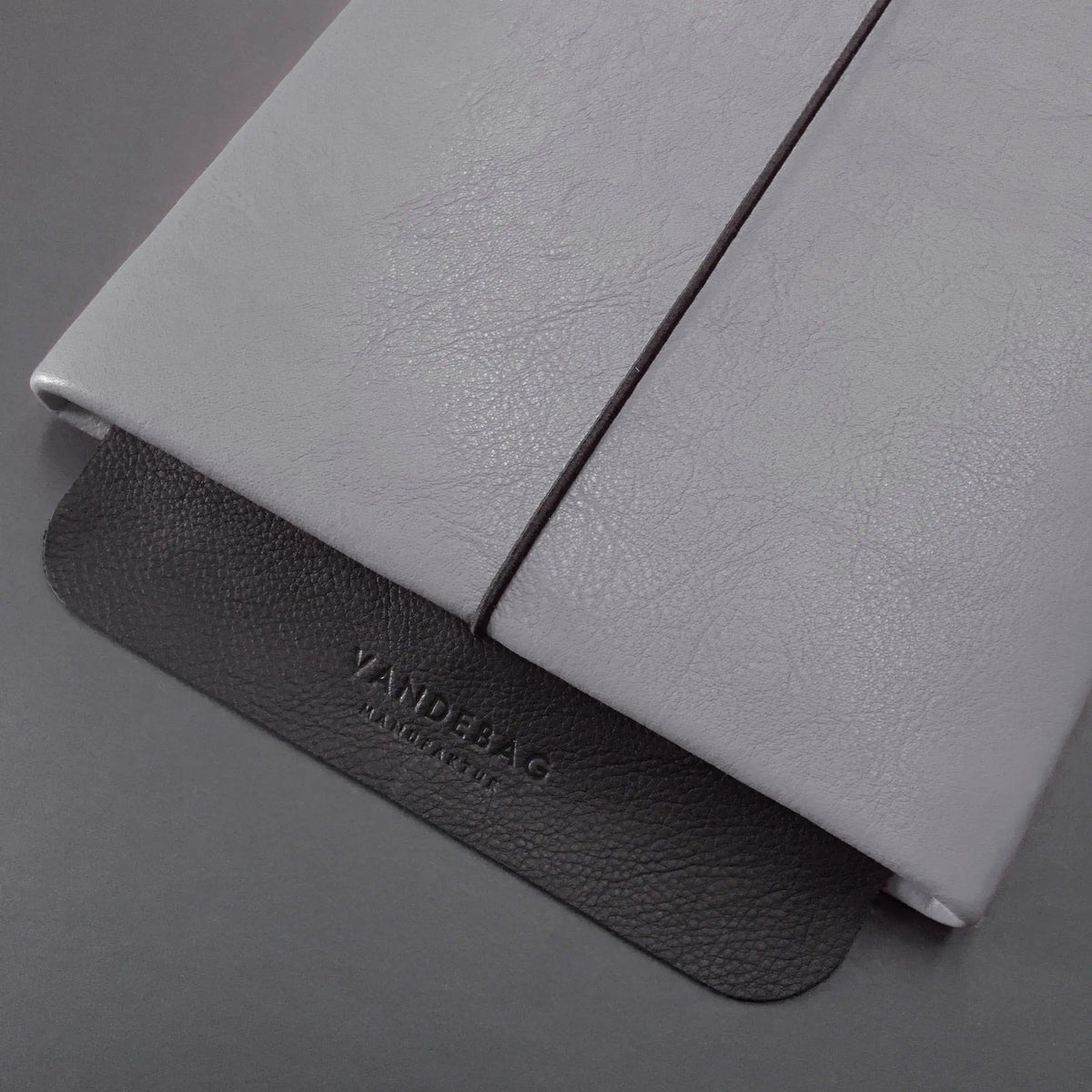 schwarze Verschlussklappe einer grauen Macbookhülleaus Leder mit Vandebag Prägung