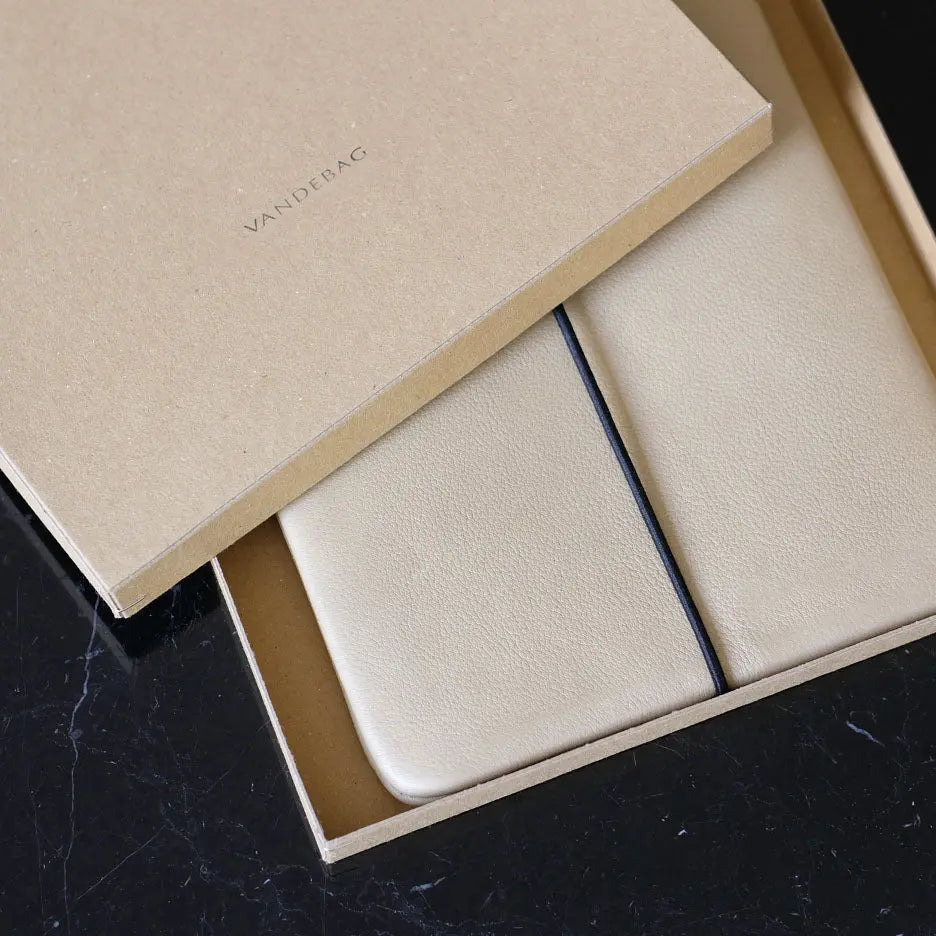 beige Lederhülle liegt in einer Produktbox auf einem schwarzen Marmortisch
