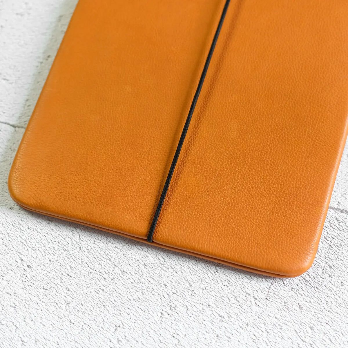 iPadhülle aus orangefarbenem Leder mit leichter Narbung und schwarzem Verschlussgummi